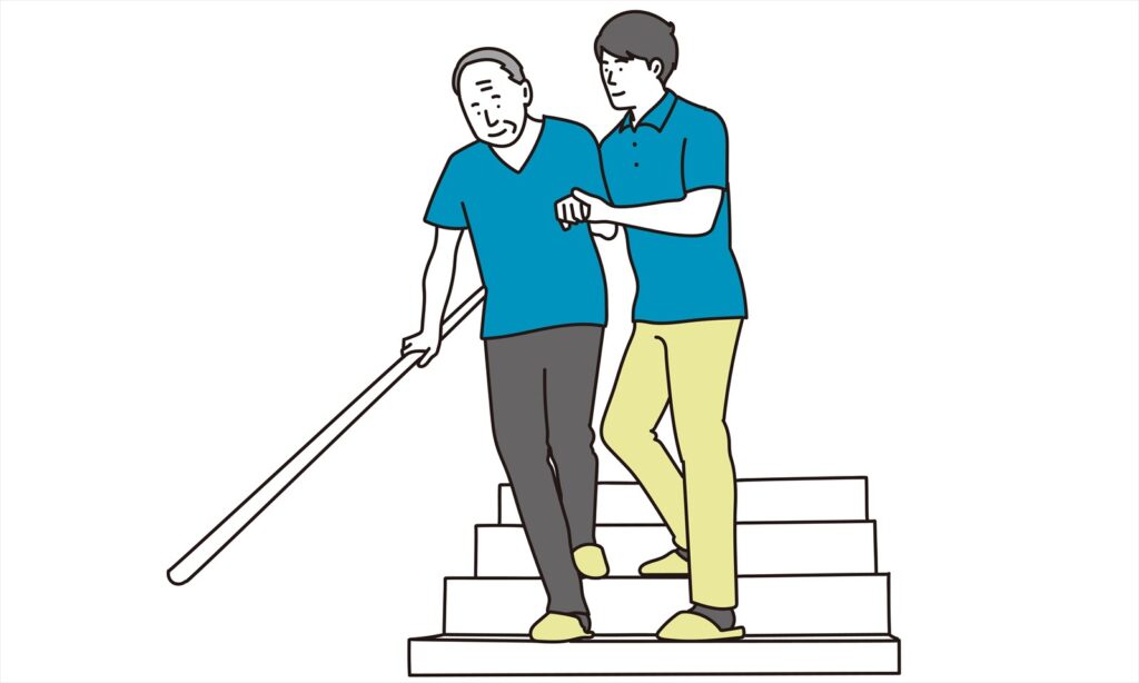 階段を降りる高齢者と介護する若者